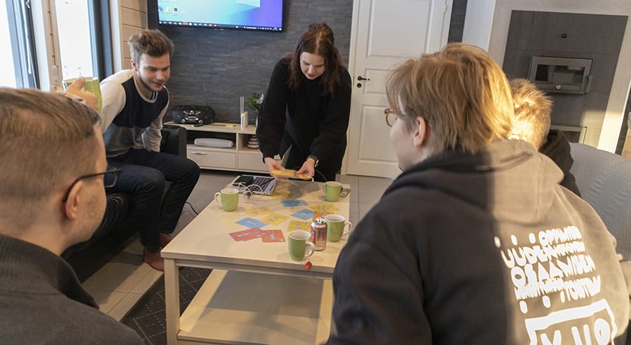 Opiskelijaryhmä työskentelemässä yhteisen pöydän ääressä.