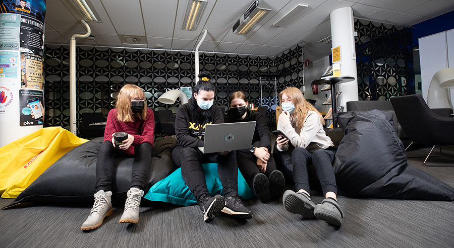Opiskelijat istuvat ja katselevat kannettavaa tietokonetta.