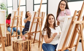 Nuoria naisia studiotiloissa maalamassa tauluja yhdessä.