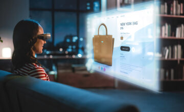Nuori nainen käyttää virtuaalilaseja istuessaan kotona. ja tekemässä online ostoksia.
