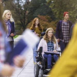 Opiskelijoita kävelemässä ulkona. Yksi opiskelija istuu pyörätuolissa.